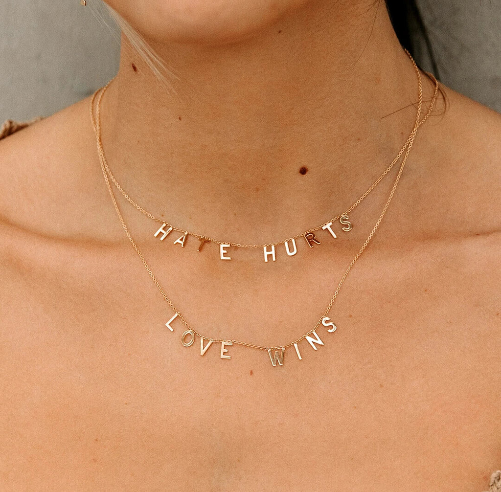 ModSet Jewelry "love wins" "hate hurts" necklaces in 14k yellow gold on a female model