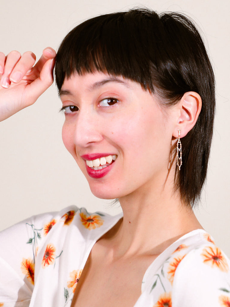 laughing female model wearing block name post drop earrings in white gold spelling Tammy