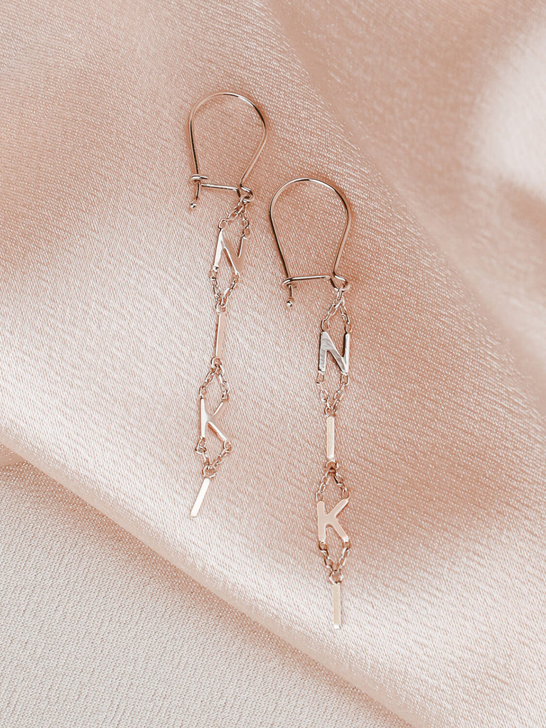close photo detail of block name drop earrings in 14k white gold