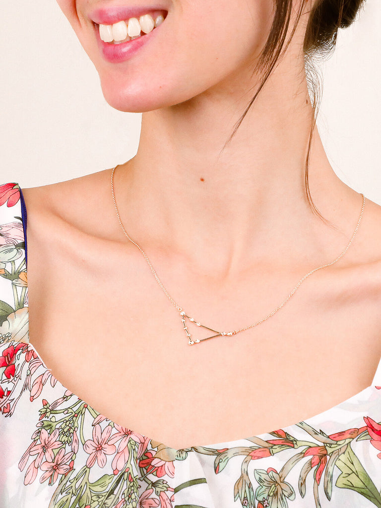 Gold Capricorn Constellation necklace on a smiling female model's neck