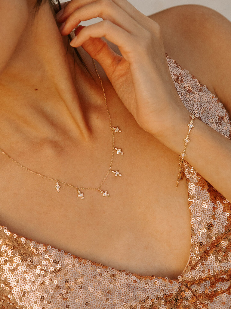 detail photo of  gold evening star bracelet and necklace on a female model in sequin dress