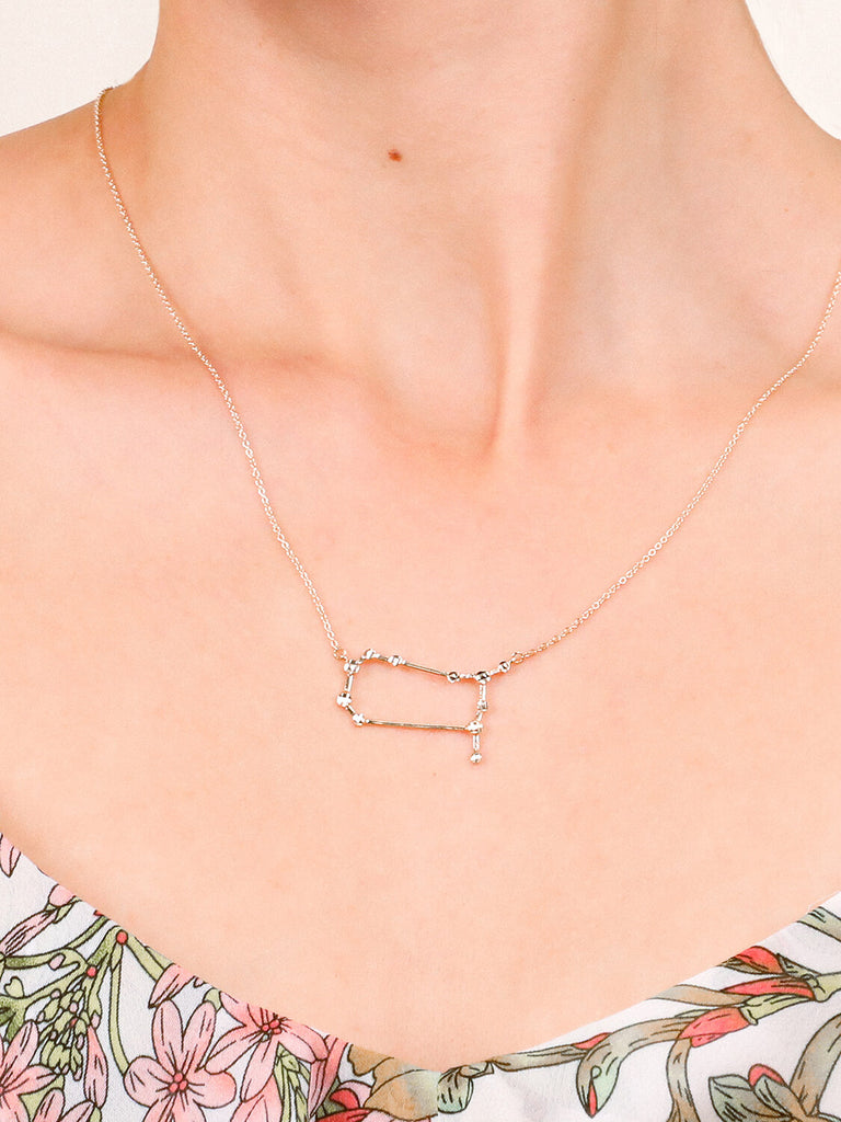 Gold Gemini Constellation necklace on a female model's neck