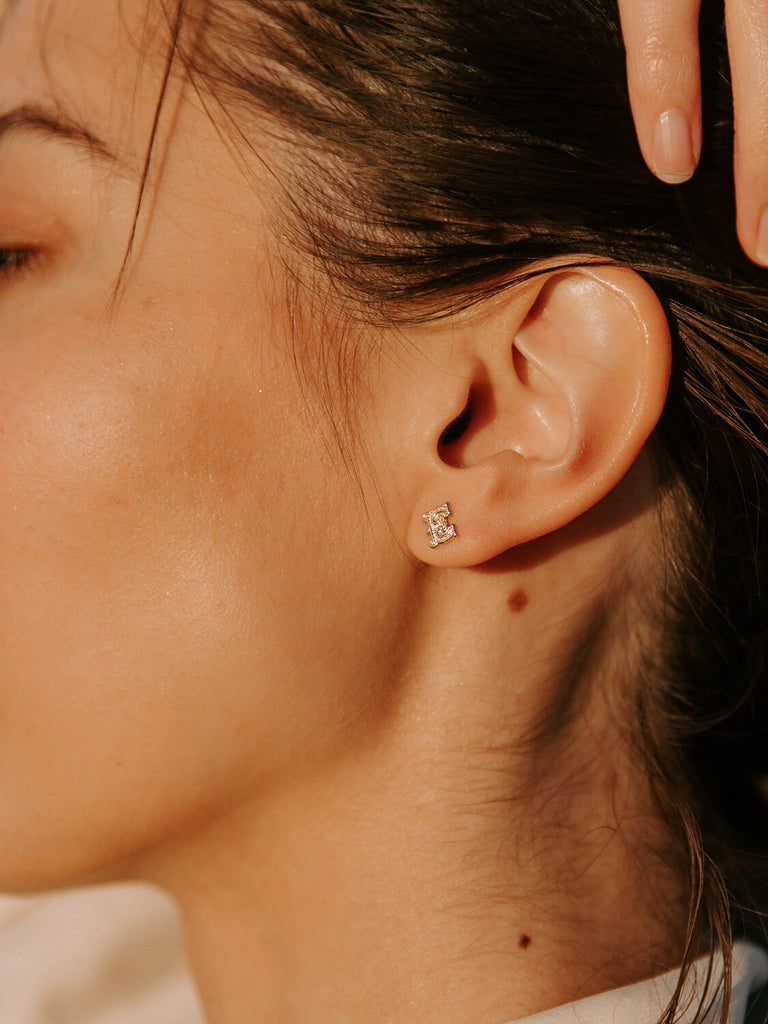detail photo of gold gothic monogram post earrings on female model