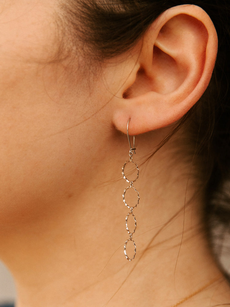 close up photo of female model wearing halo curled earrings in white gold