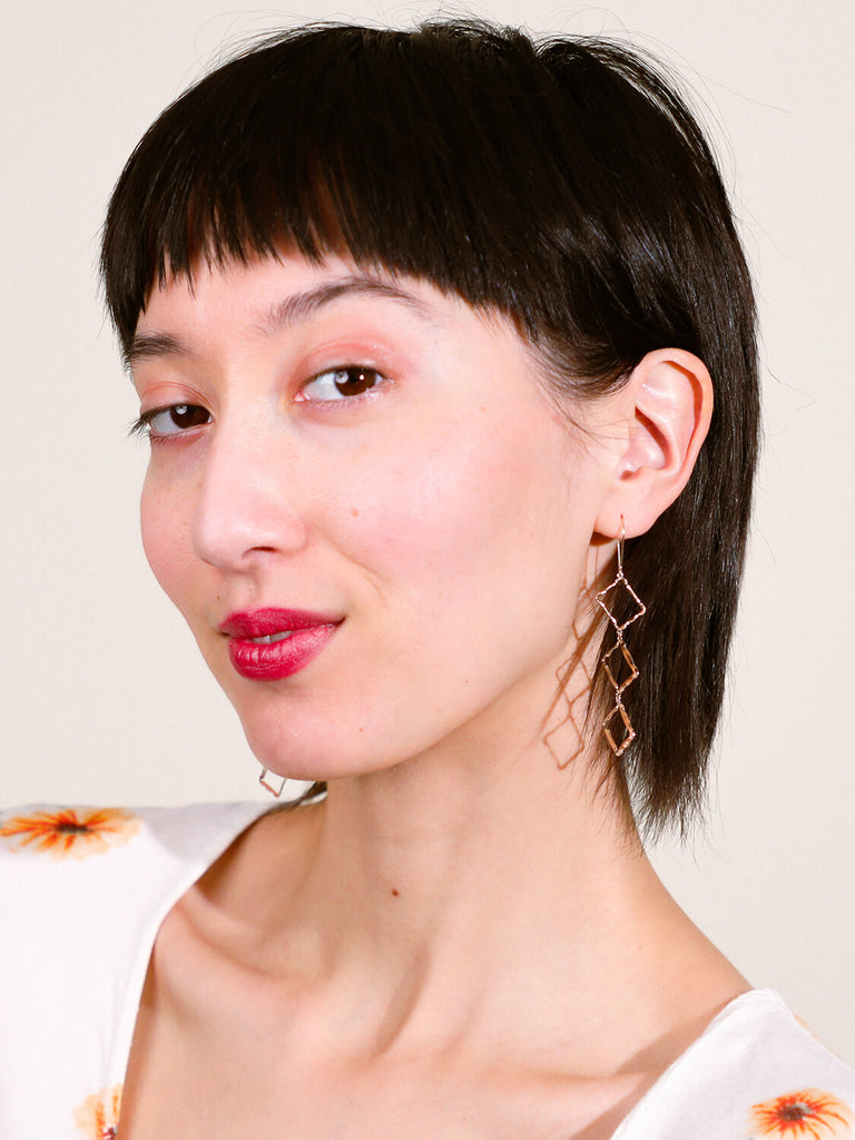 happy female model wearing Halo rectangle stacked earrings looking at the camera