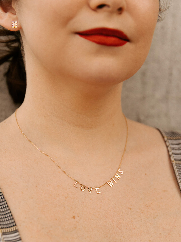 "Love Wins" message collection necklace in yellow gold on female model