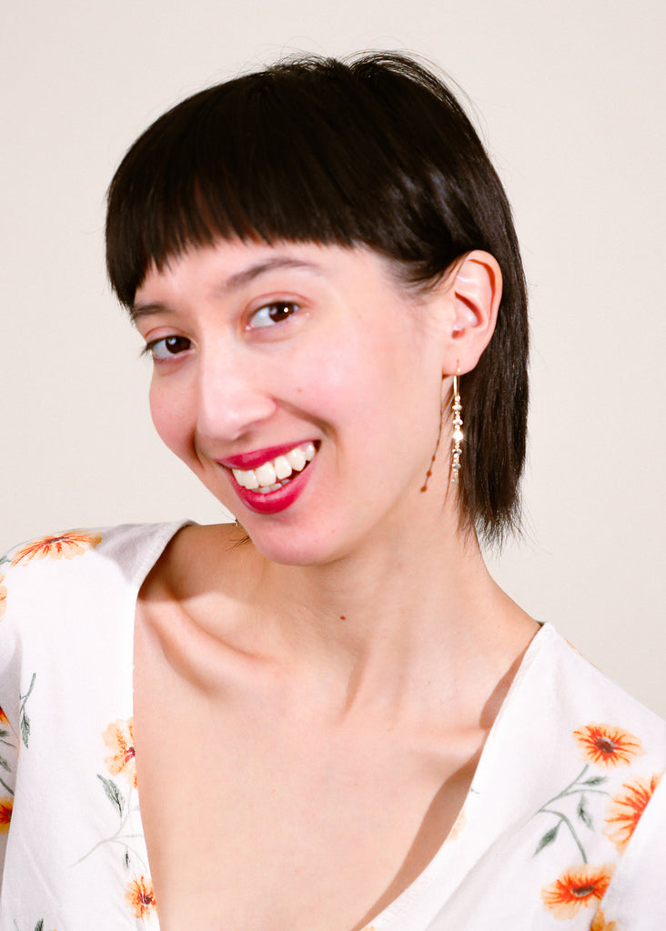 happy model wearing mermaid's beauty oval earrings in yellow gold looking at the camera 