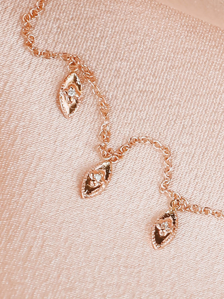 detail photo of 14k yellow gold artemis leaf necklace on pink satin with diamonds