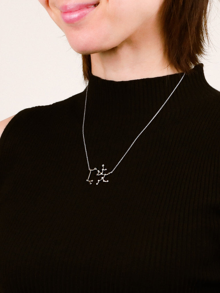 Photo of sterling silver Sagittarius zodiac constellation necklace from ModSet jewelry on smiling female model's neck