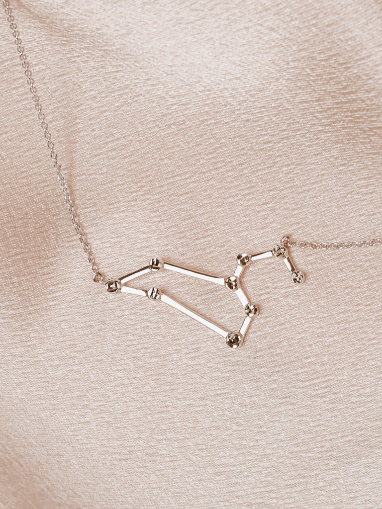 Detail photo of sterling silver Leo zodiac constellation necklace from ModSet jewelry on pink fabric
