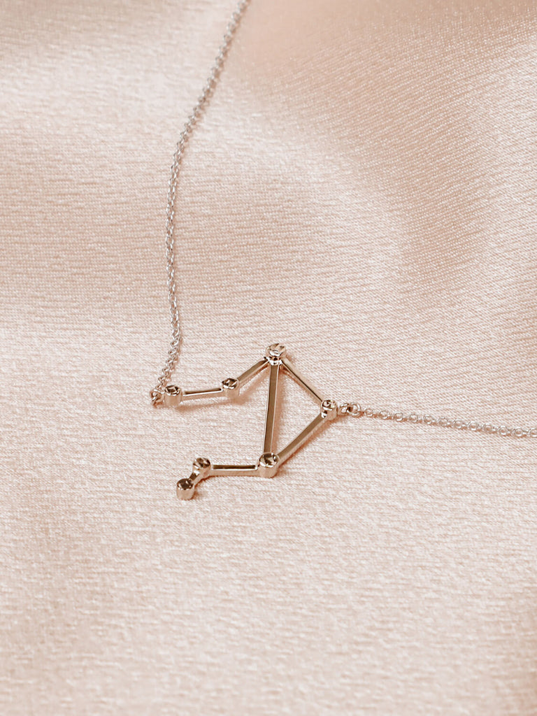 Detail photo of sterling silver Libra zodiac constellation necklace from ModSet jewelry on pink fabric