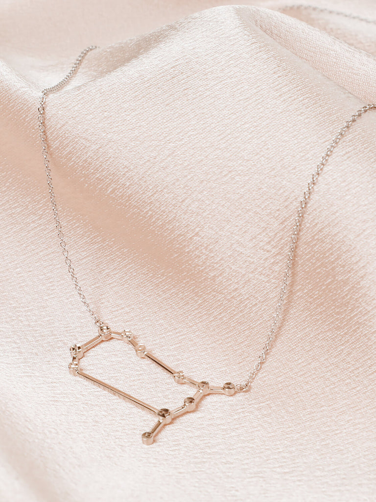 Close detail photo of sterling silver Gemini zodiac constellation necklace from ModSet jewelry on pink fabric