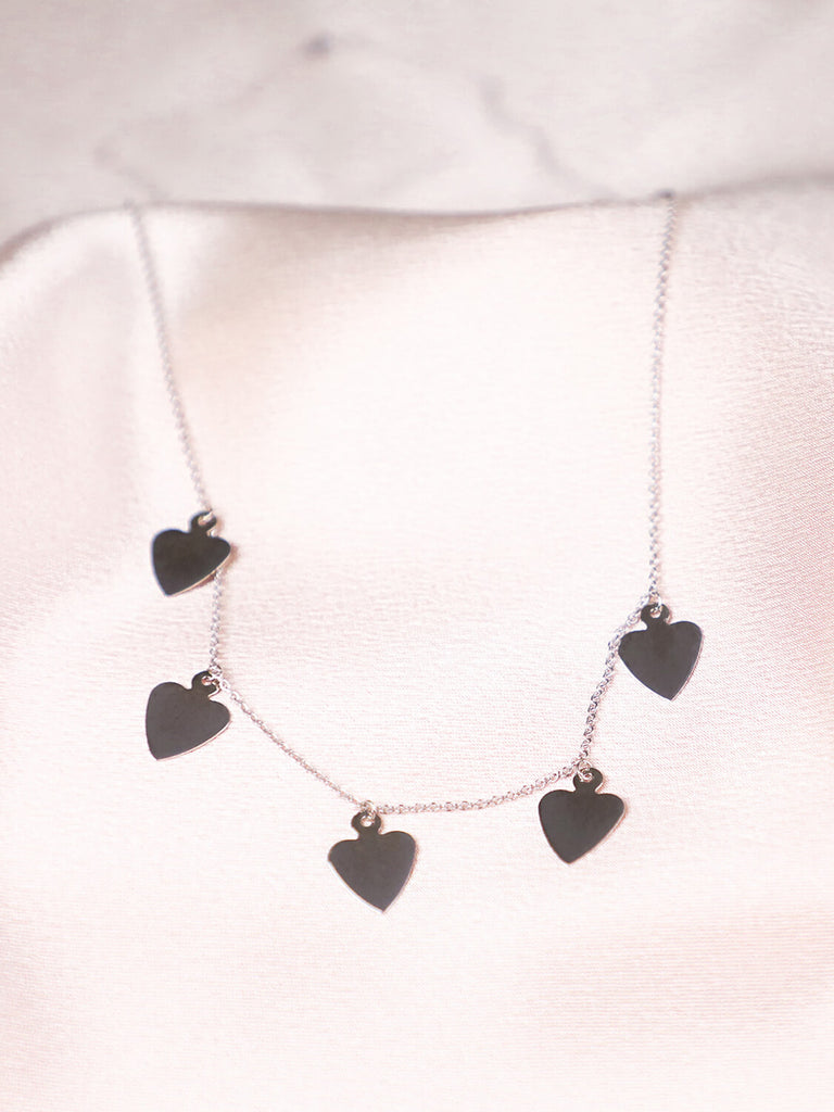 detail photo of 14k White gold Queen of Hearts Love Never Dies necklace against pink satin