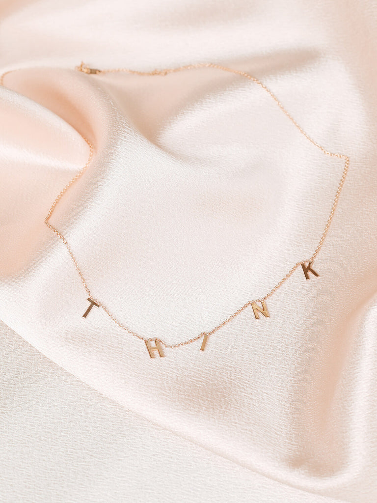 "Think" Message Necklace in yellow gold on pink satin
