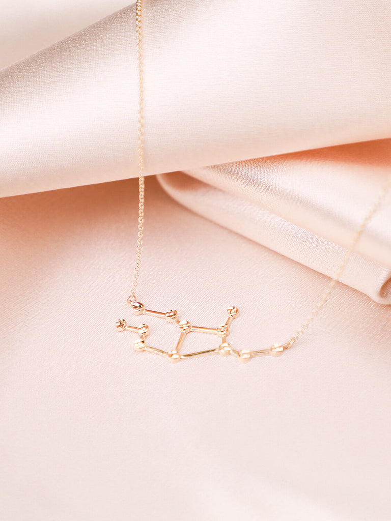  gold virgo constellation necklace laying down on satin background