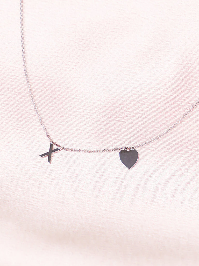 detail shot of 14k White gold XO Love Never Dies necklace against pink satin