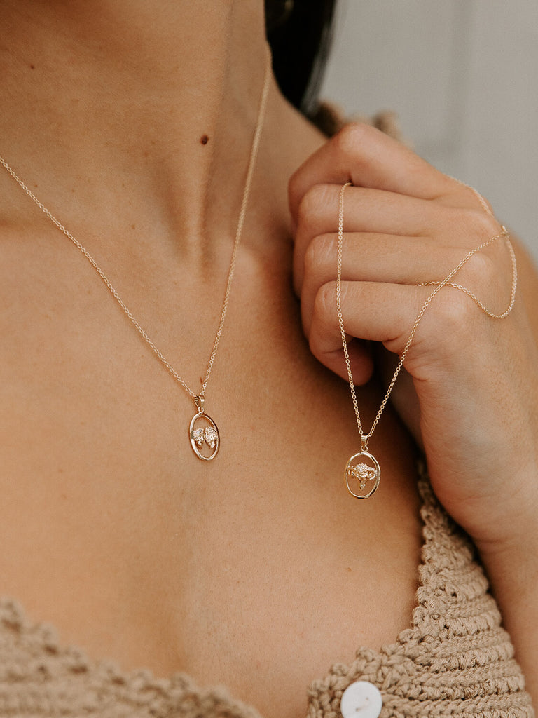 photo of girl model holding gemini and aries zodiac layered charm pendants necklaces in yellow gold
