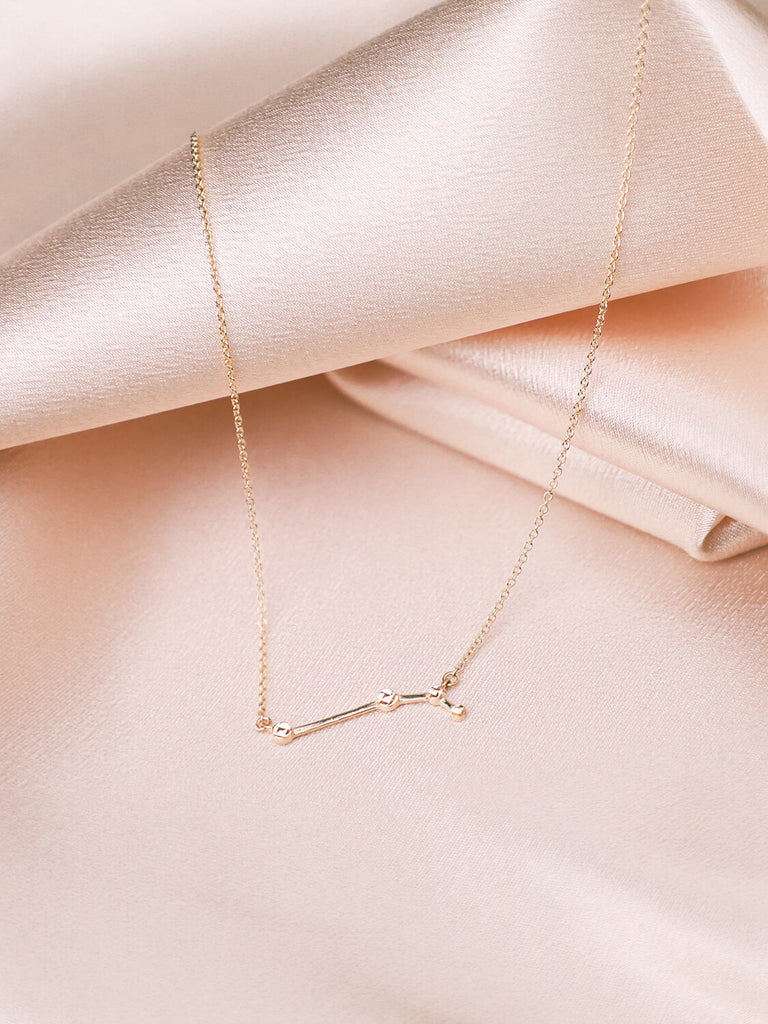 beautiful gold Aries constellation necklace against satin background