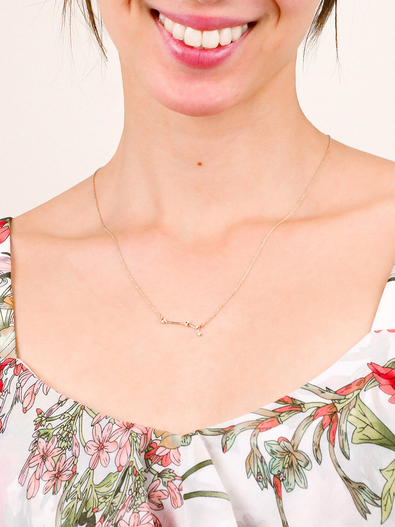 Gold Aries Constellation necklace on a happy female model's neck