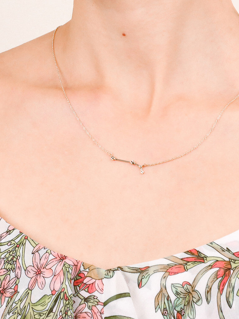 Gold aries Constellation necklace on a female model's neck