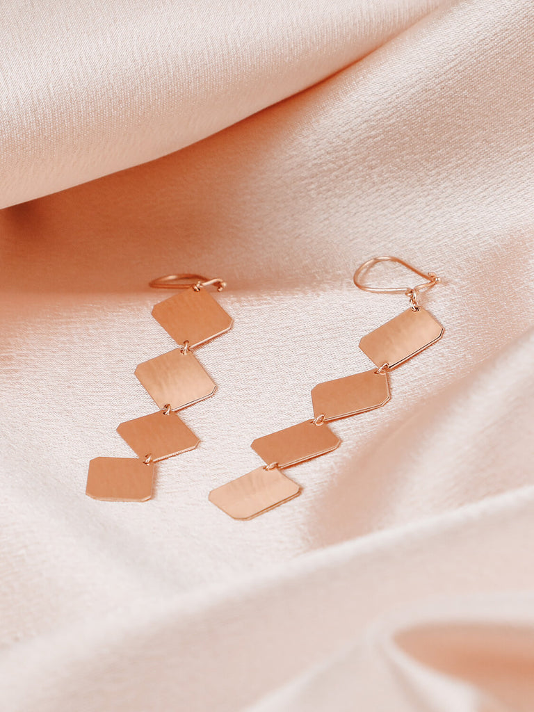 detail shot of artemis plate earrings in yellow gold on satin background 