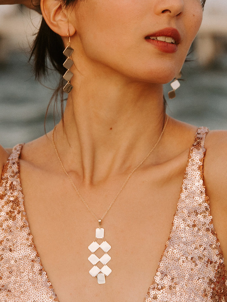 gold Artemis plate earrings and necklace on a model who is looking to the side in sequin dress