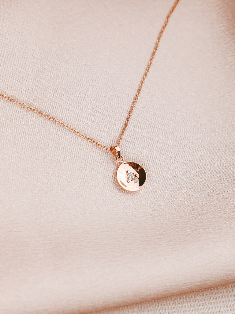 detail photo of Artemis power necklace with diamond in center in yellow gold on pink satin background