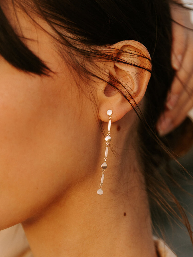 Close up of model wearing gold Artemis shield earrings during golden hour