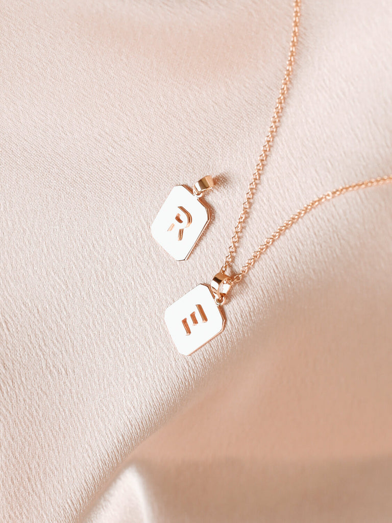 Close up of "R" and "E" Block Initial Necklace in yellow gold