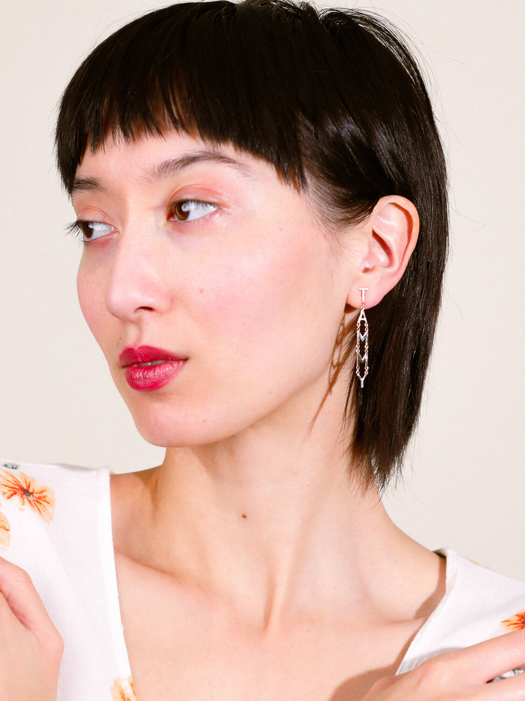 female model wearing block name post drop earrings in white gold spelling Tammy