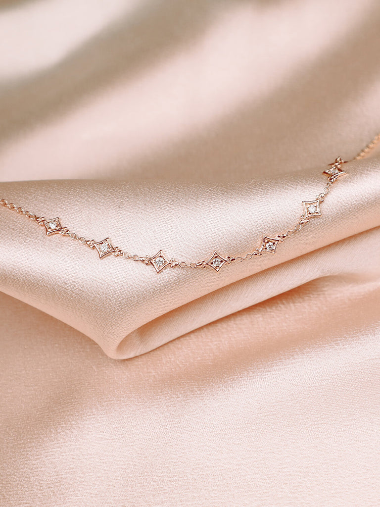detail photo of evening star bracelet with diamonds against pink satin background 