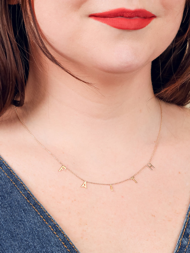 close up of Faith message necklace in yellow gold on female model