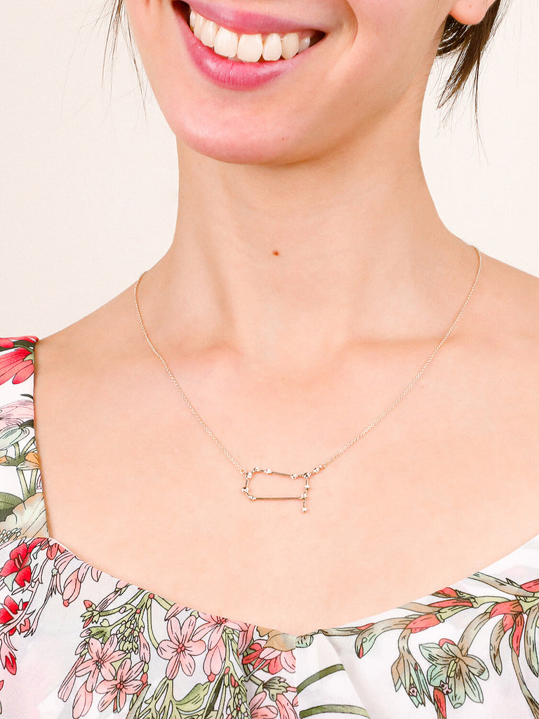 Gold Gemini Constellation necklace on a happy smiling female model's neck