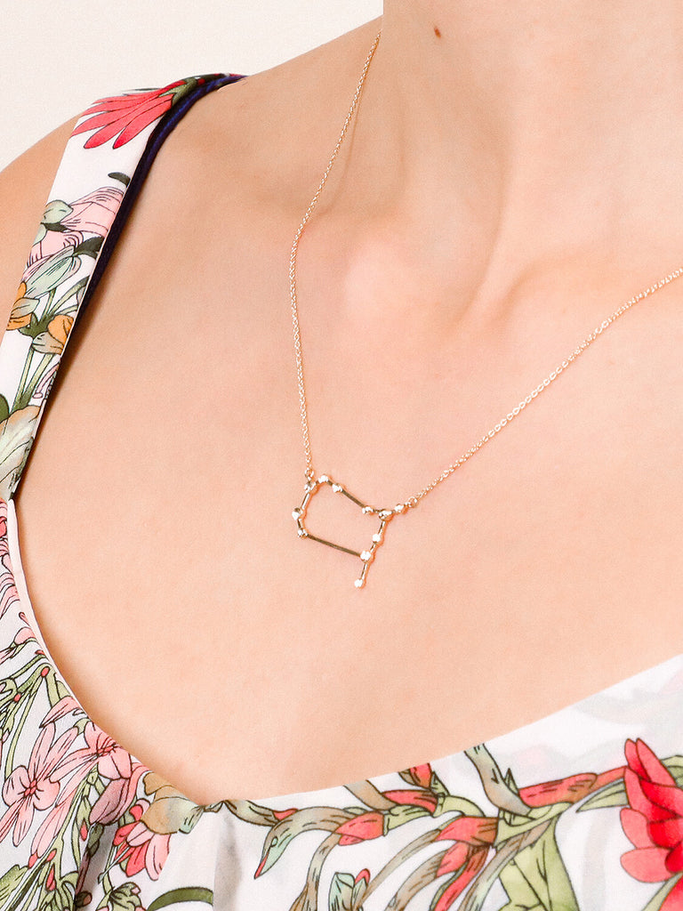 detail shot of Gold gemini Constellation necklace on a female model's neck