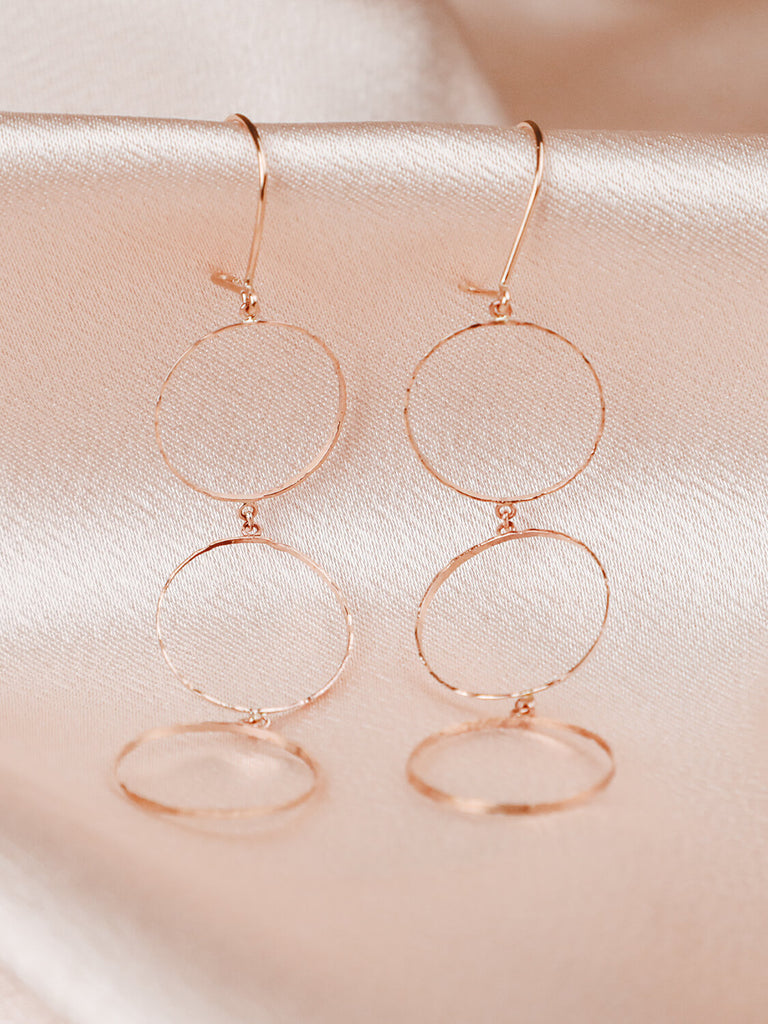 detail photo of halo stacked earrings in yellow gold on pink satin fabric
