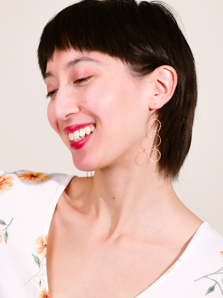 laughing  female model wearing yellow gold halo stacked earrings looking away