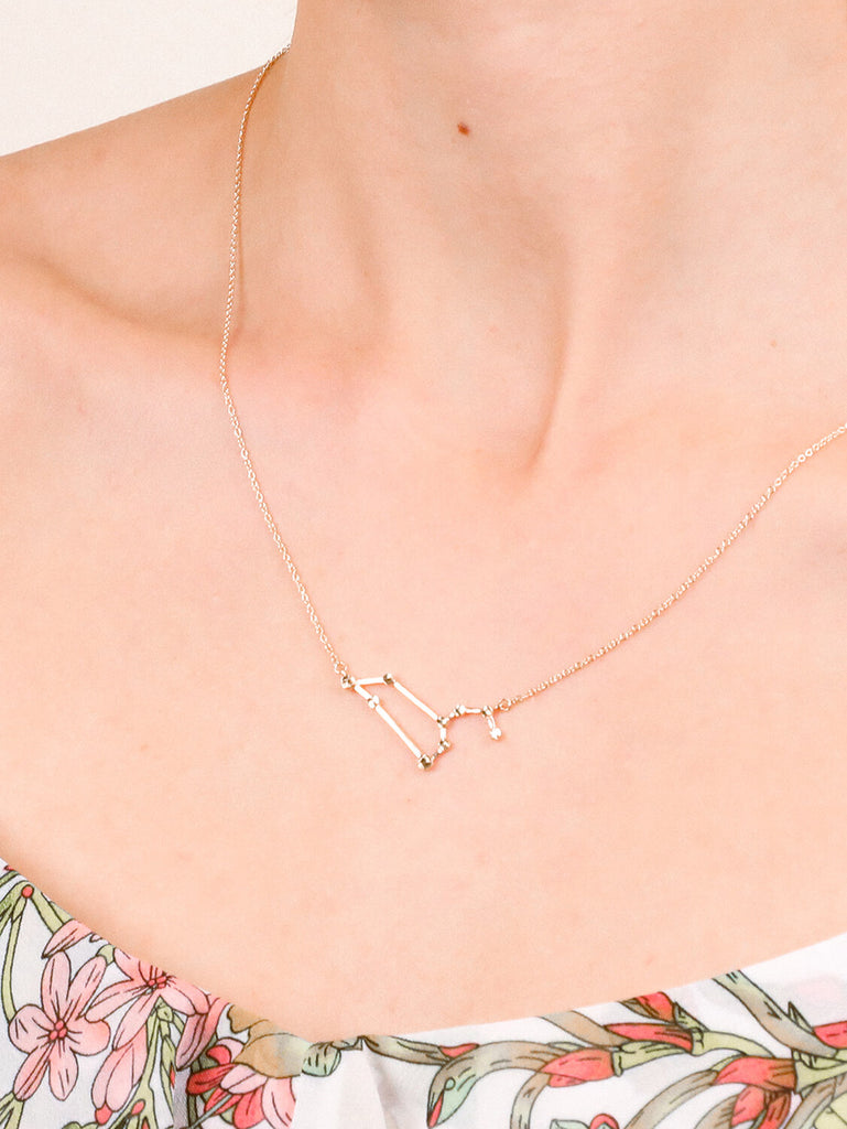 Detail shot of Gold Leo Constellation necklace on a female model's neck
