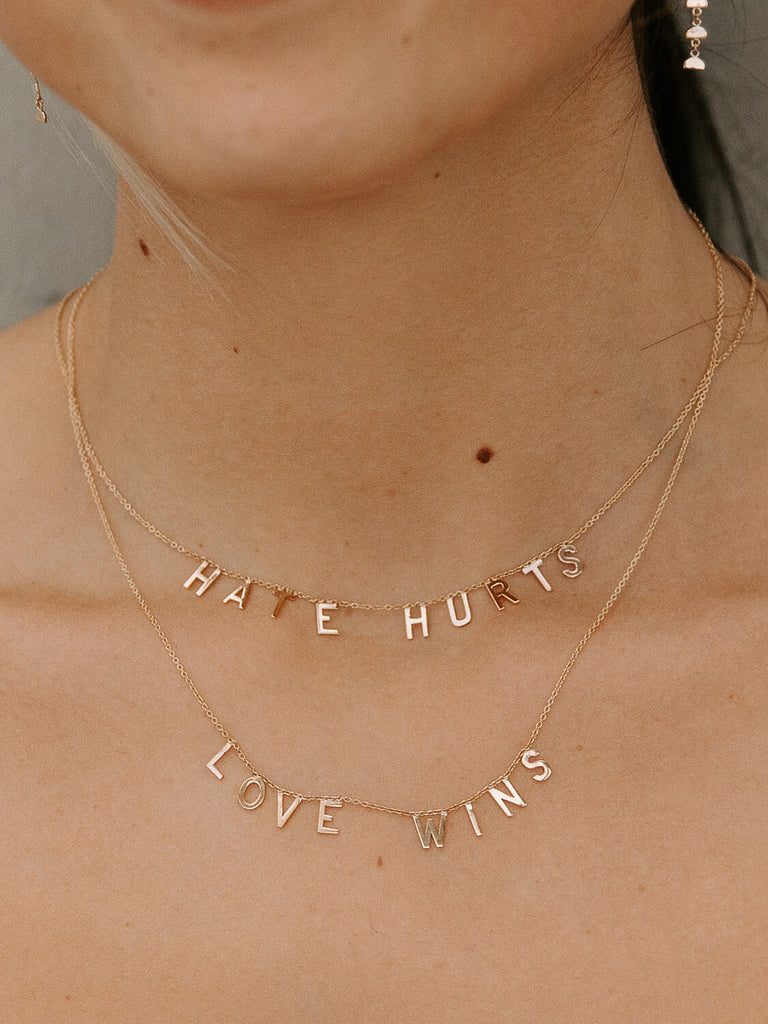 "Love Wins" message collection necklace in yellow gold on tan female model