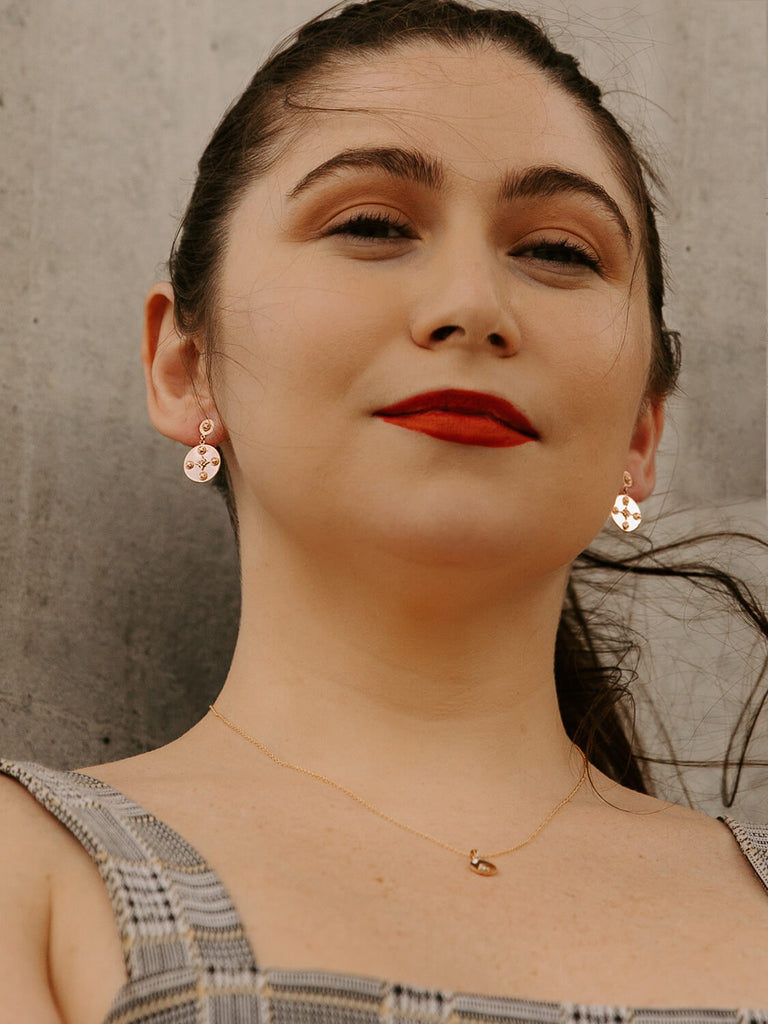 Female model wearing Midnight Celestial Earrings in rose gold with red lipstick 