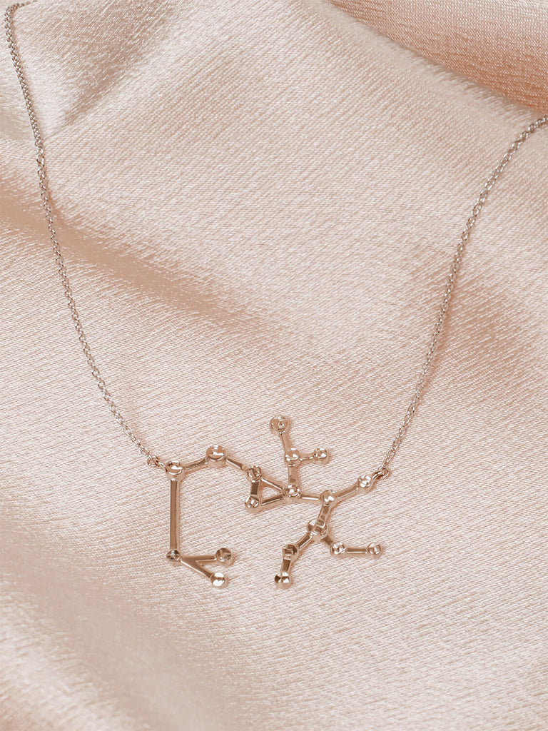 Photo of sterling silver Sagittarius zodiac constellation necklace from ModSet jewelry on pink fabric