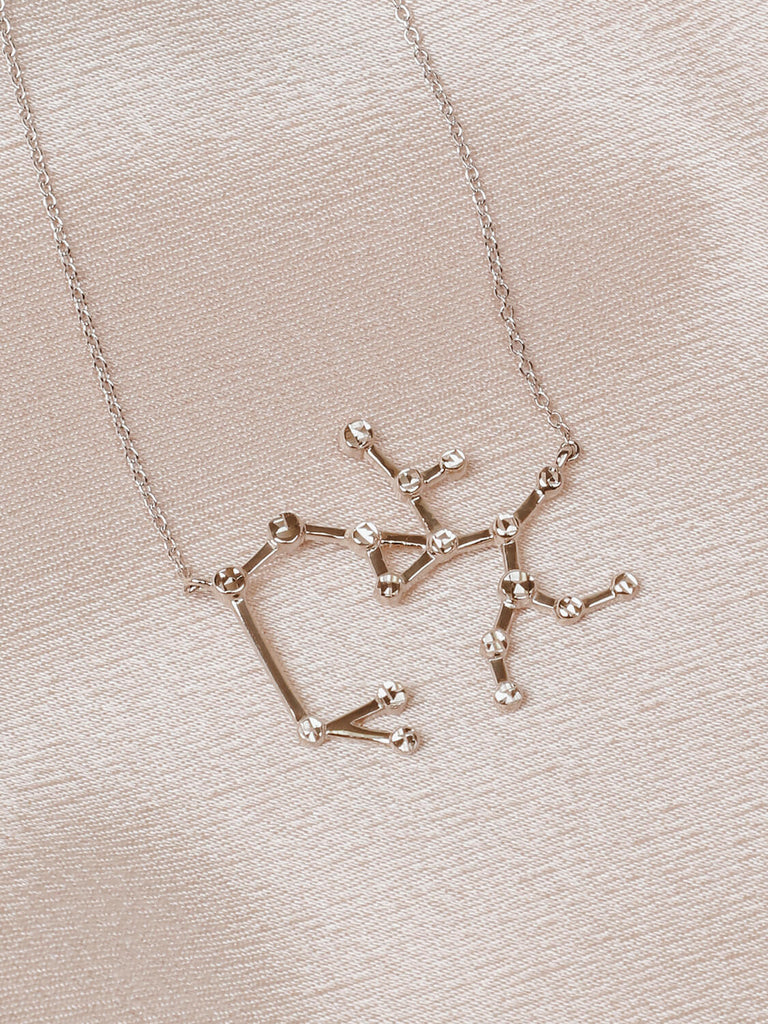 Close detail photo of sterling silver Sagittarius zodiac constellation necklace from ModSet jewelry on pink fabric