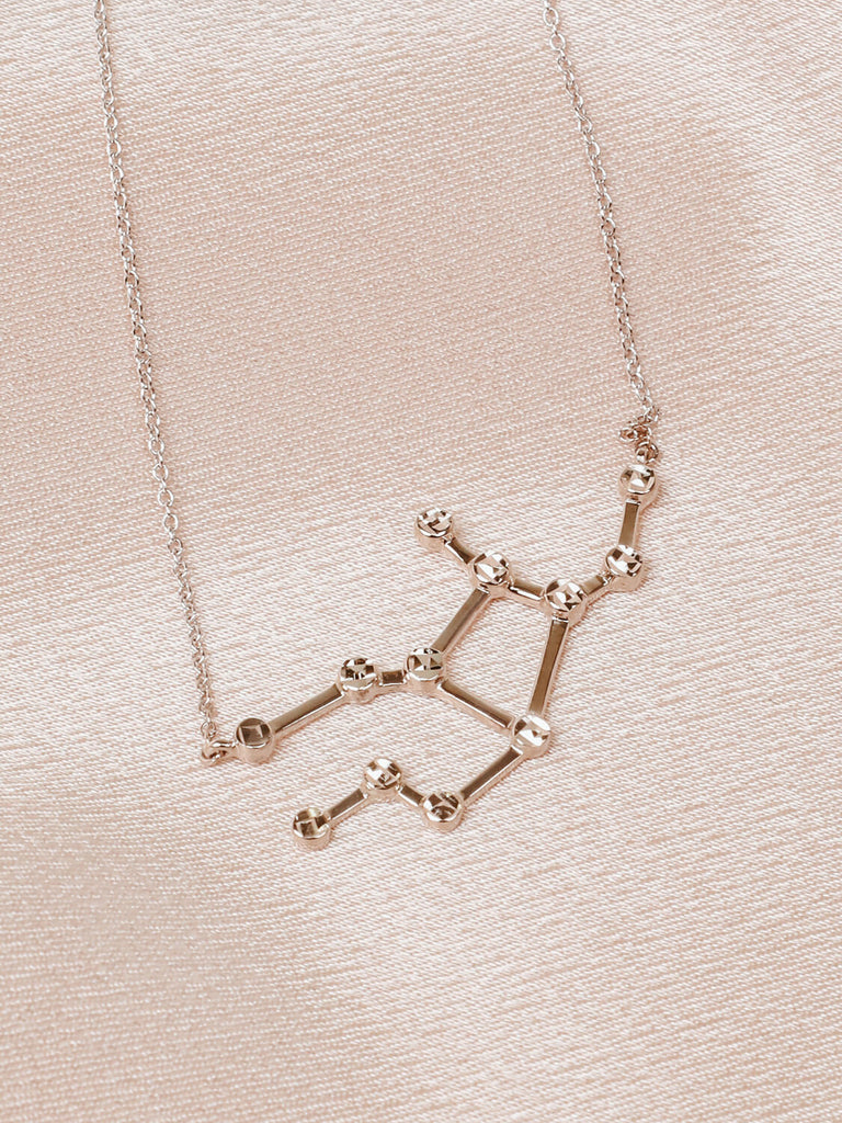 Close detail photo of sterling silver Virgo zodiac constellation necklace from ModSet jewelry on pink fabric