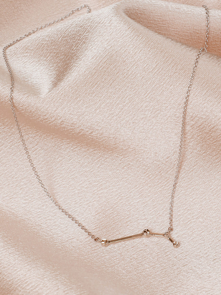 Close detail photo of sterling silver Aries zodiac constellation necklace from ModSet jewelry on pink fabric