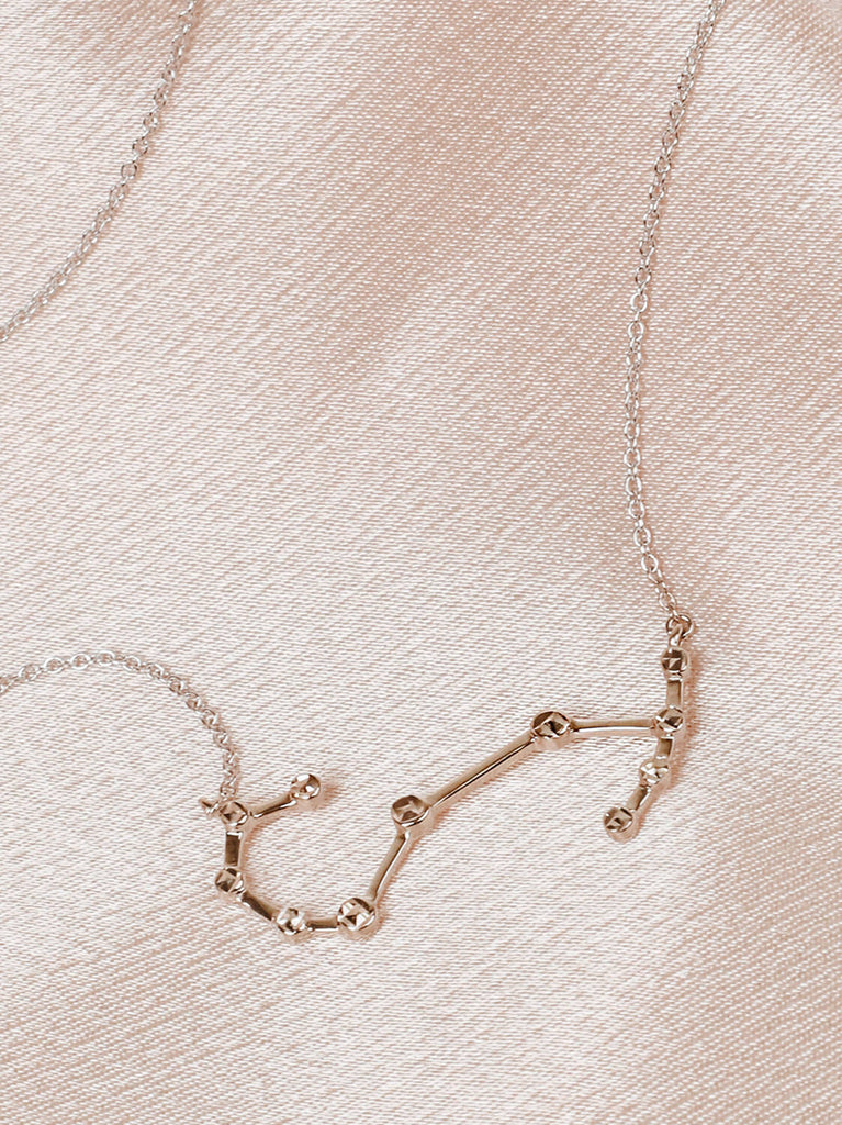 Close detail photo of sterling silver Scorpio zodiac constellation necklace from ModSet jewelry on pink fabric