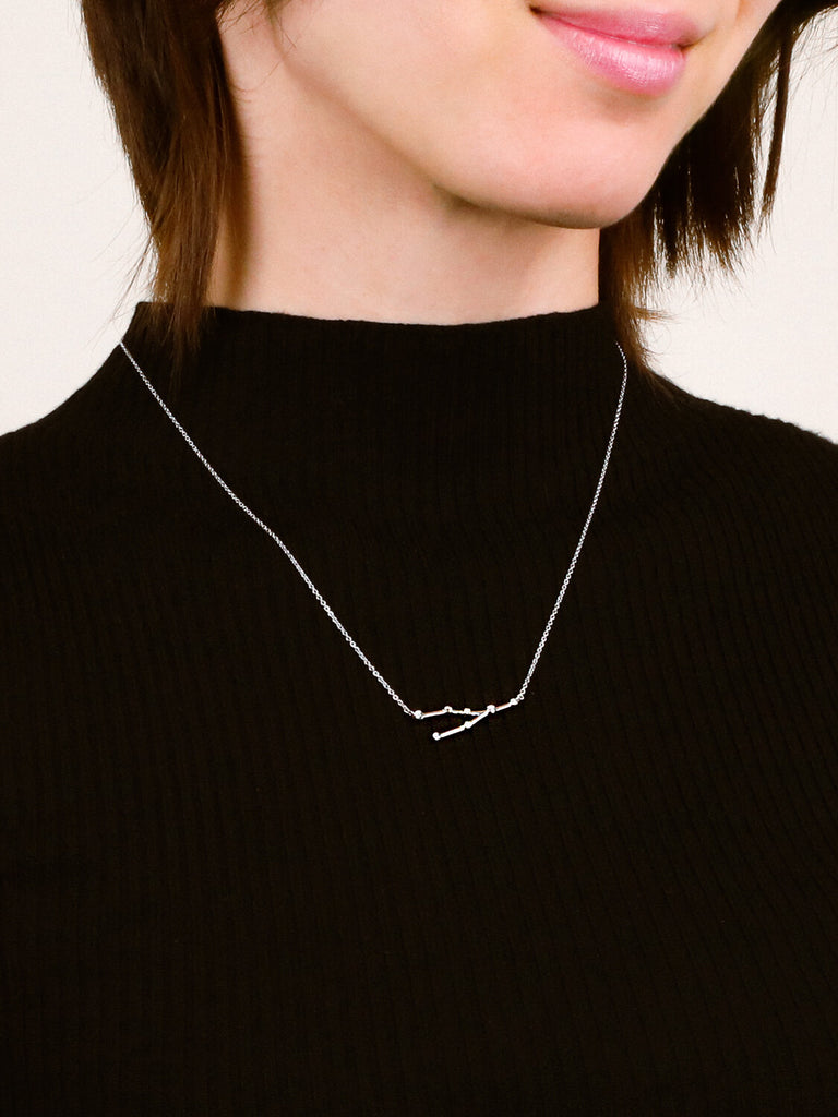 Photo of sterling silver Taurus zodiac constellation necklace from ModSet jewelry on smiling woman's neck