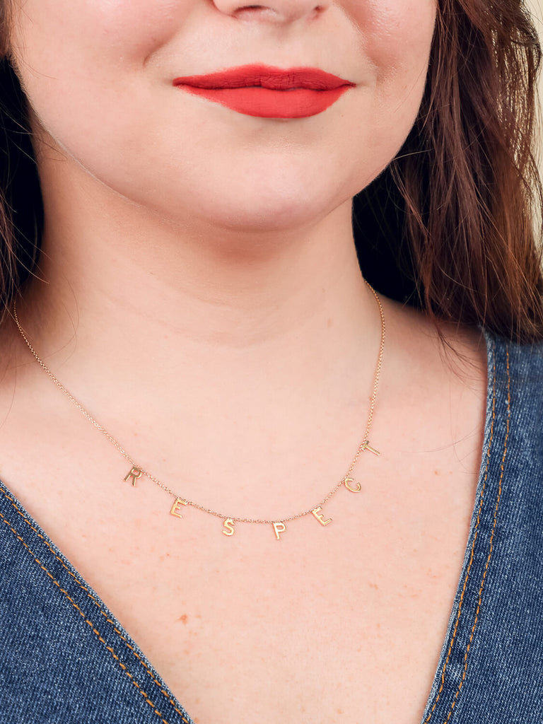 close up of happy female model wearing yellow gold "Respect" message necklace 