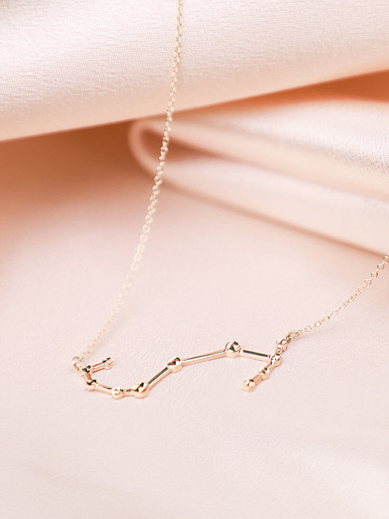 gold scorpio constellation necklace laying down on satin background