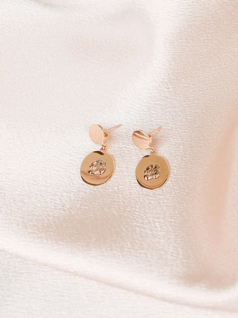 pair of "B" Script initial post earrings in yellow gold on pink satin