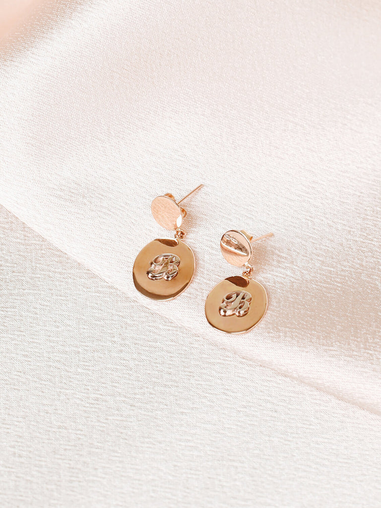 detail photo of pair of "B" Script initial post earrings in yellow gold on pink satin