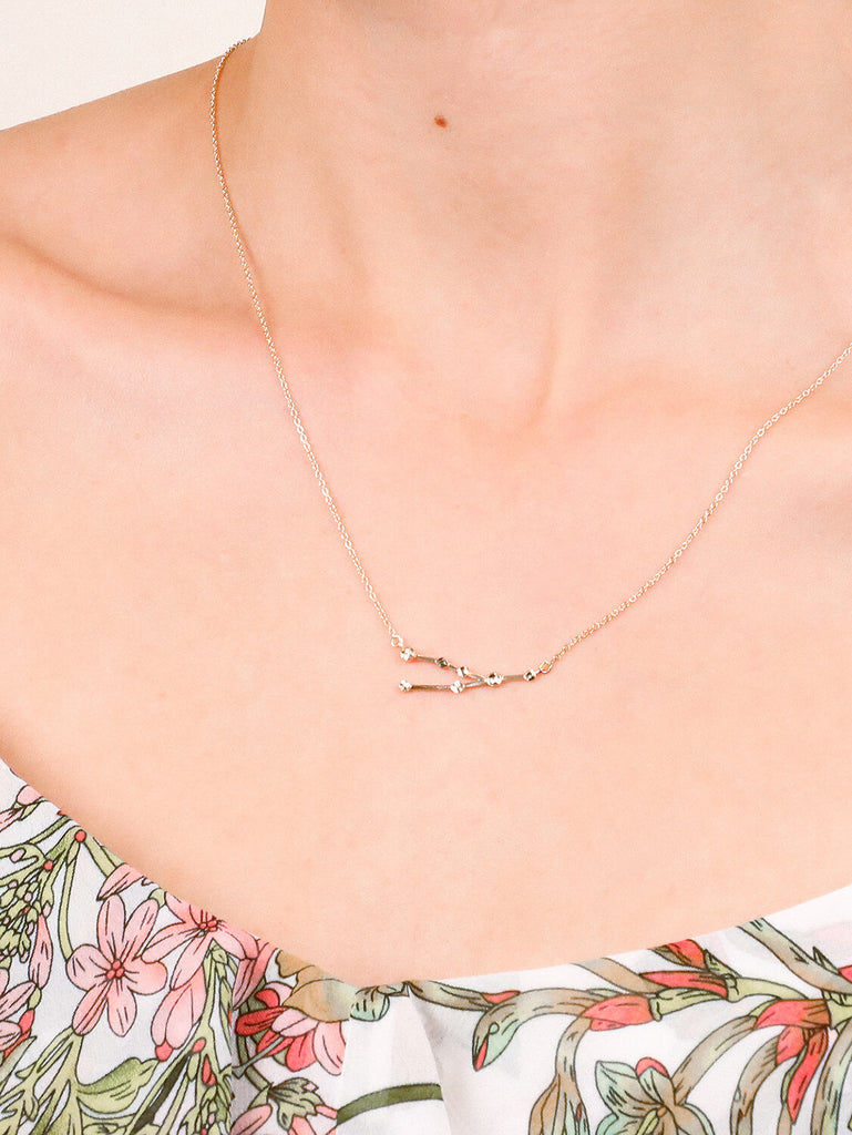 detail shot of Gold Taurus Constellation necklace on a female model's neck